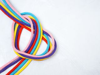En forma de corazón hecho de cinco cuerdas multicolores retorcidas sobre un fondo de hormigón. concepto de relación creativa.